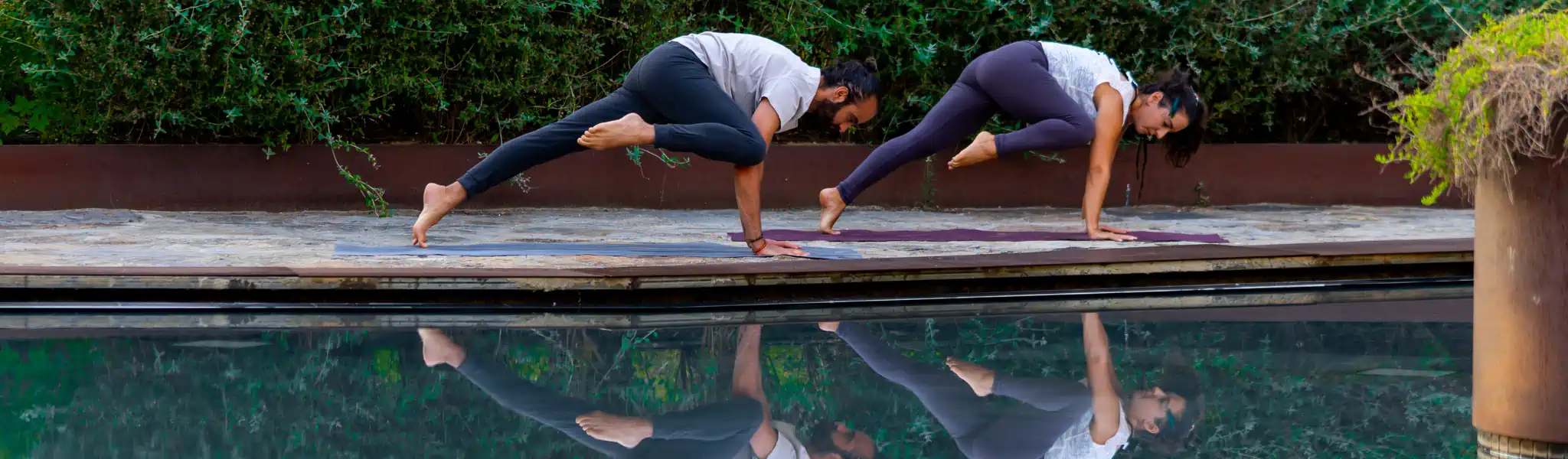 Yoga Candır Eğitmenleri Yoga Yaparken Çekilmiş bir fotoğraf, havuz başındalar ve imgeleri suya yansımış - online yoga derslerimiz ve onun yansımalarını temislen