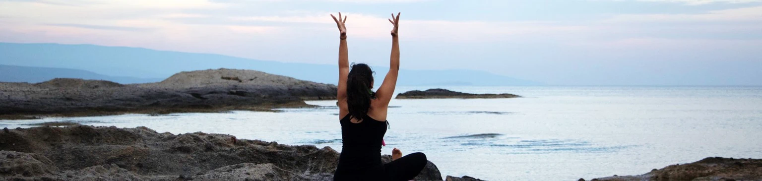 Yoga yapan bir kadının arkadan fotoğrafı, deniz kıyısında